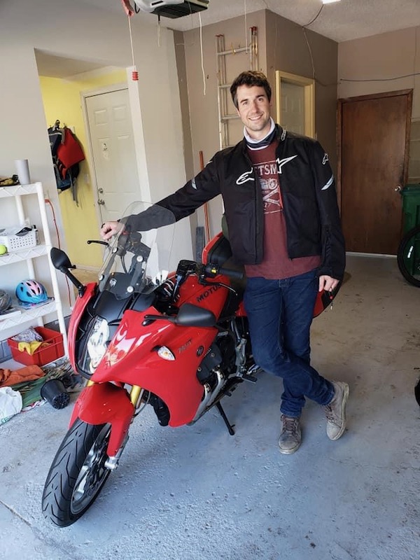 Alan standing in front of his new MOTUS motorcycle before returning home