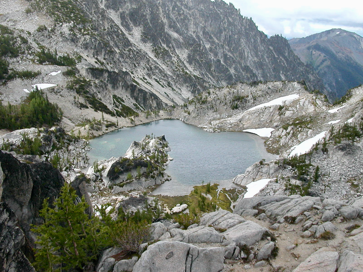 looking down on lakes, trees and snow