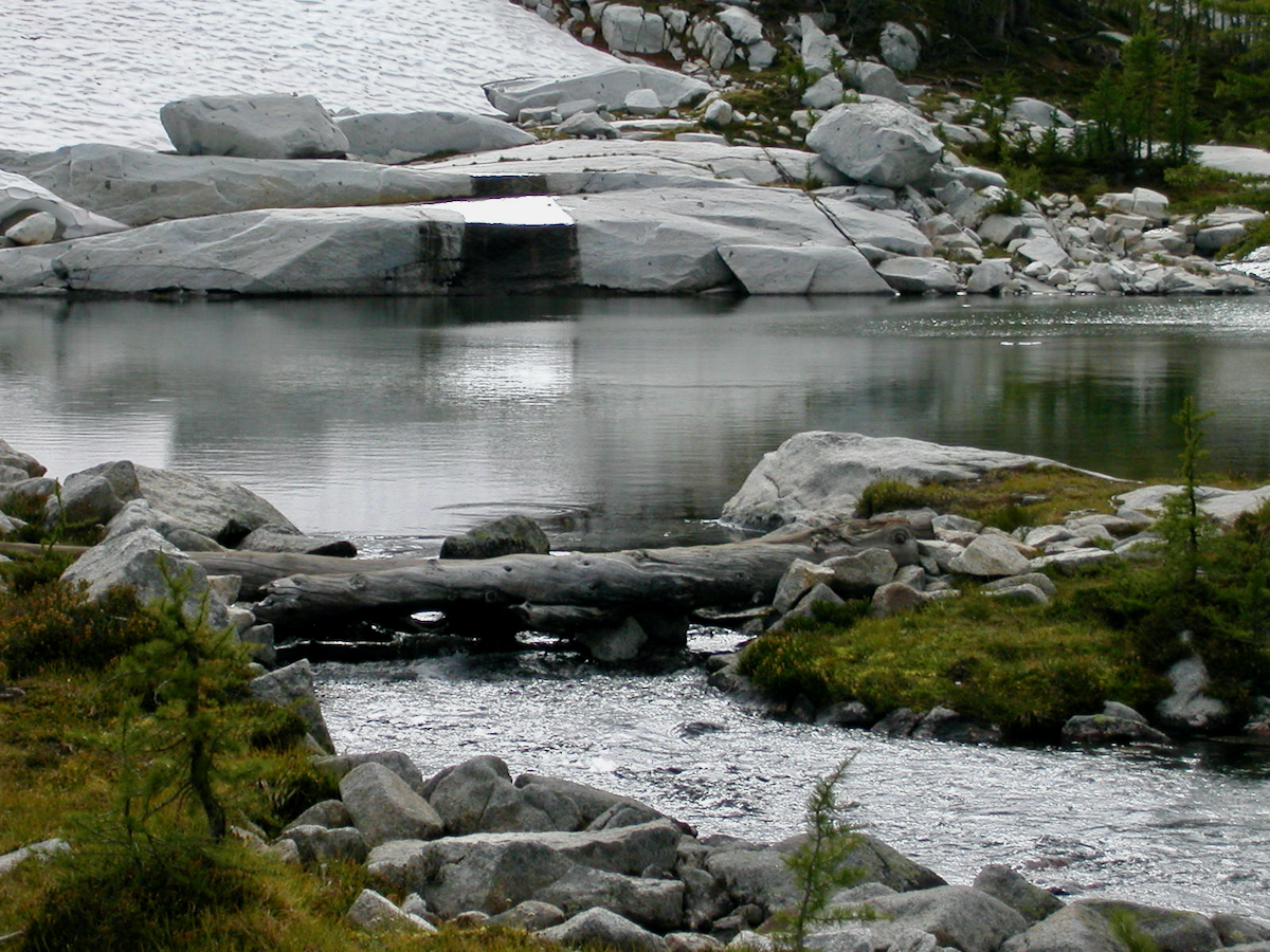 snow melting across rock into lake