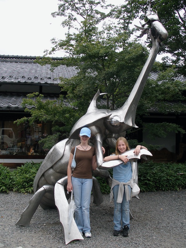 girls by metal beetle sculpture