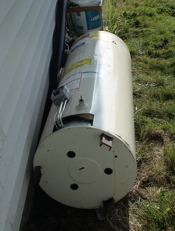 old water heater laying outside on grass