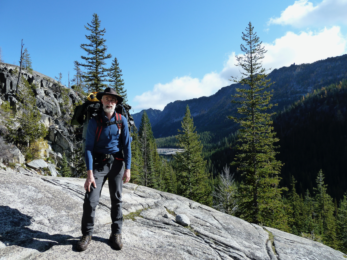 Larry on rock outcropping with entrance valley behind