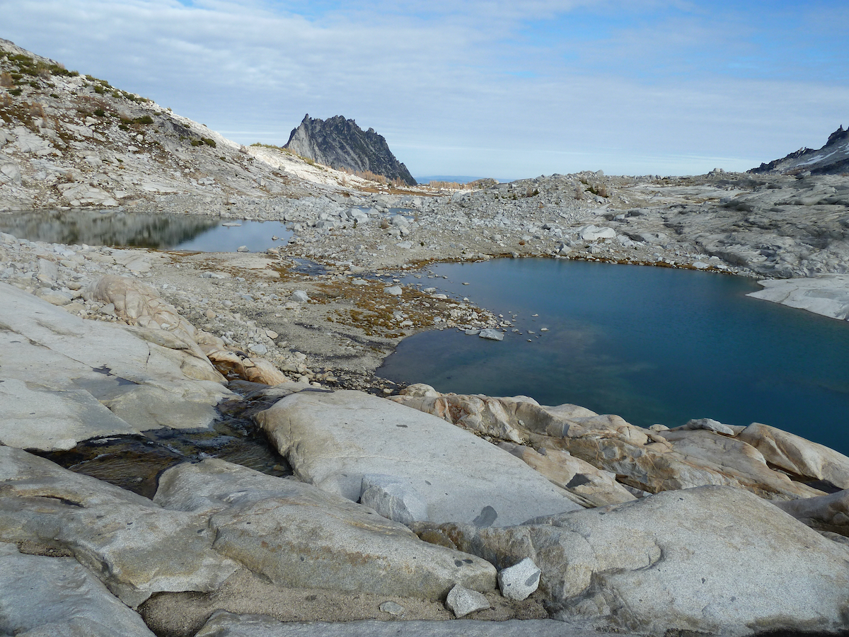 lake surrounded by gray rock, Prusik Peak in distance