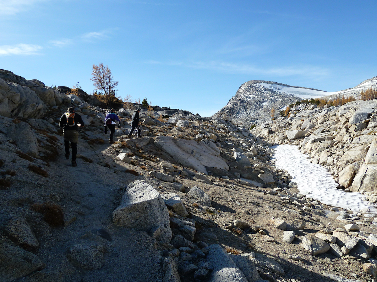 hikers uptrail and peak behind