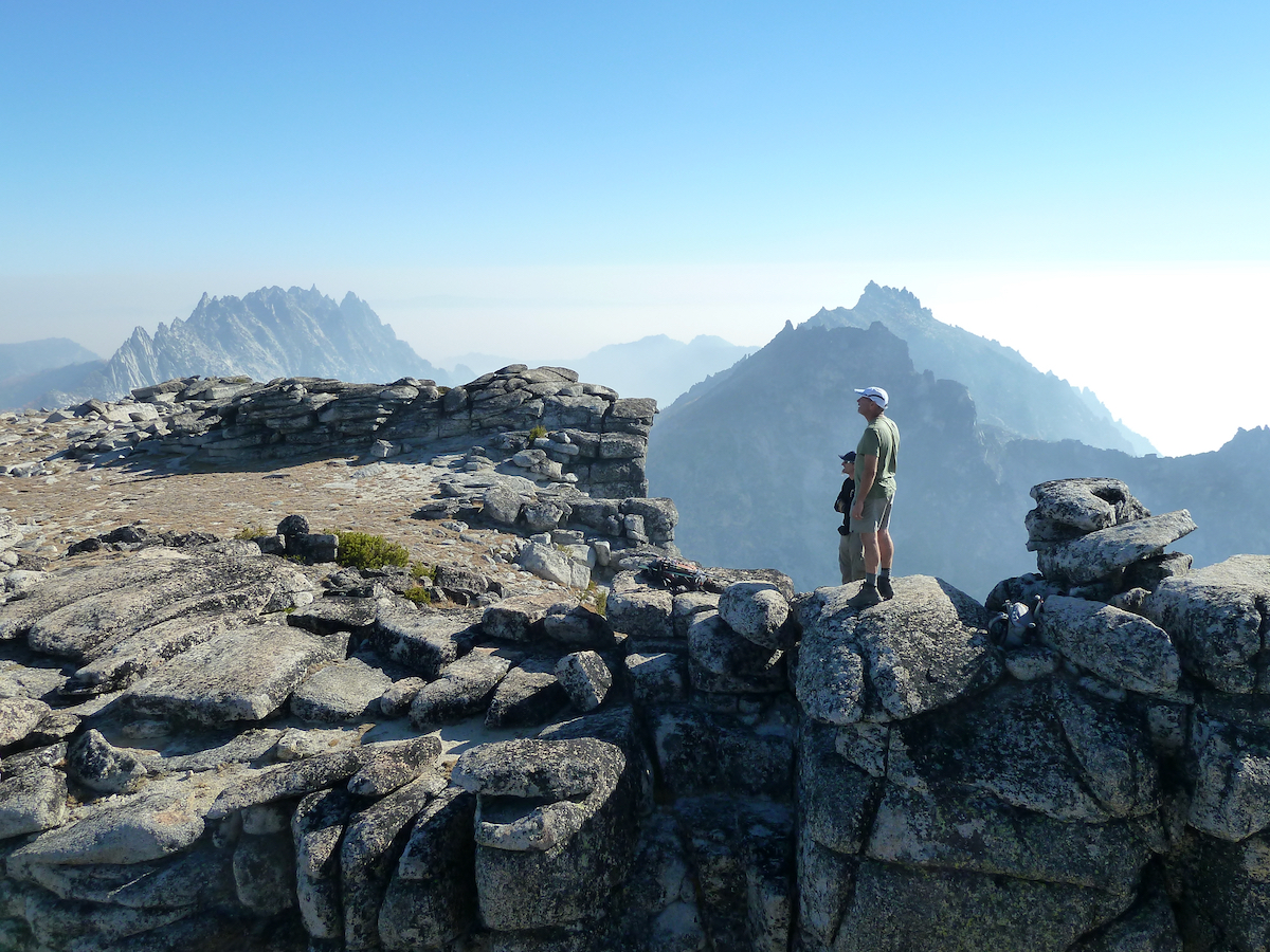 guys standing on arranged stacked rocks by meadow