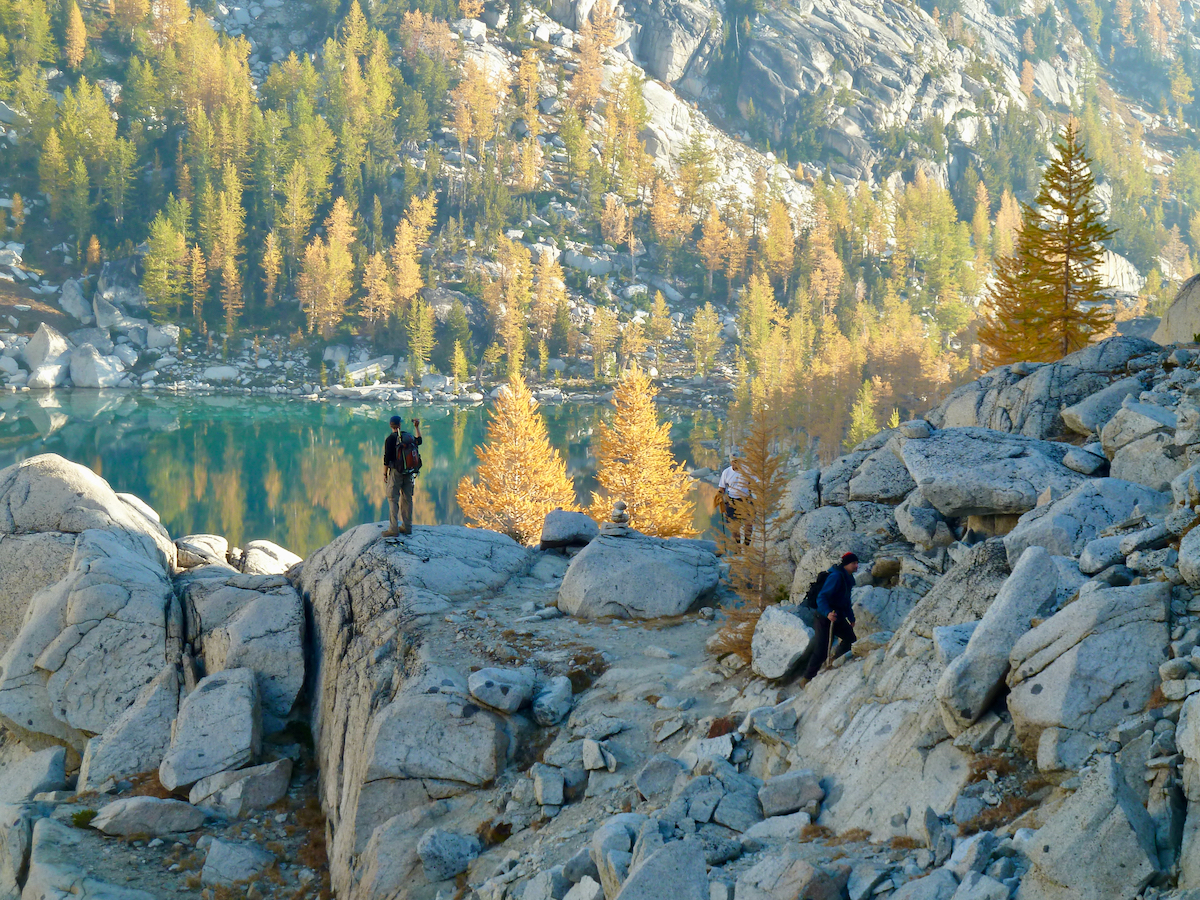 hikers along rocky trail by lakes and trees