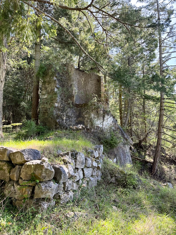 a tall kiln of stones and brick, wrapped in fencing wire to prevent falling parts