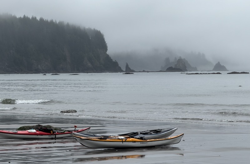kayaks on beach, islands in mist