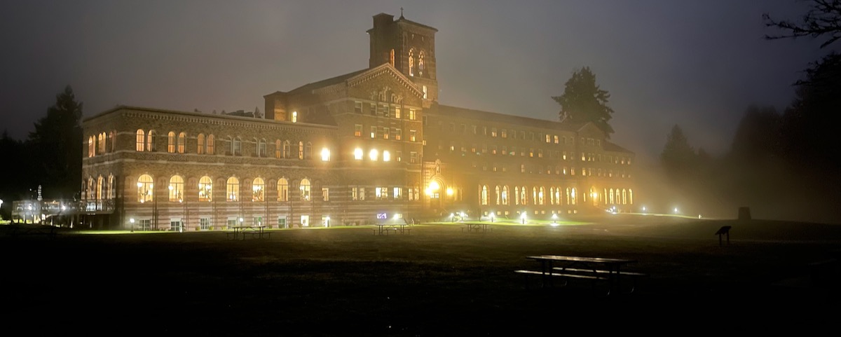 The building lit up in evening fog